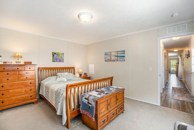 bedroom featuring a textured ceiling, crown molding, and light hardwood / wood-style flooring