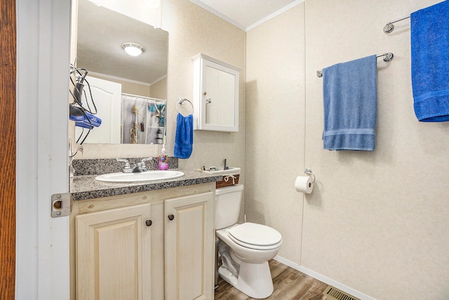 bathroom featuring vanity, toilet, wood-type flooring, and ornamental molding