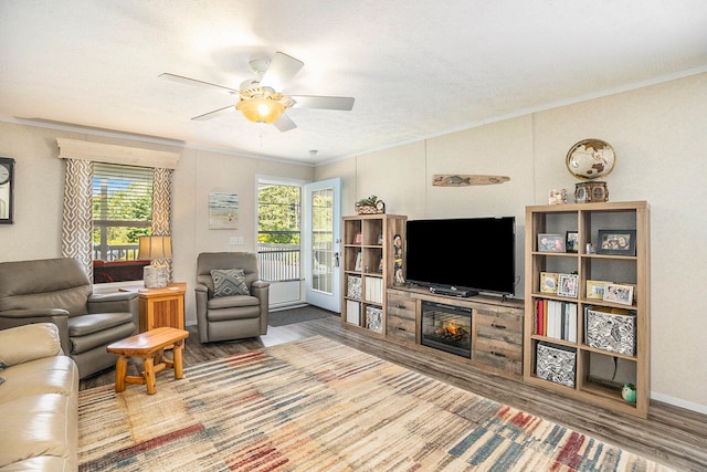 living room with ceiling fan, plenty of natural light, hardwood / wood-style floors, and ornamental molding