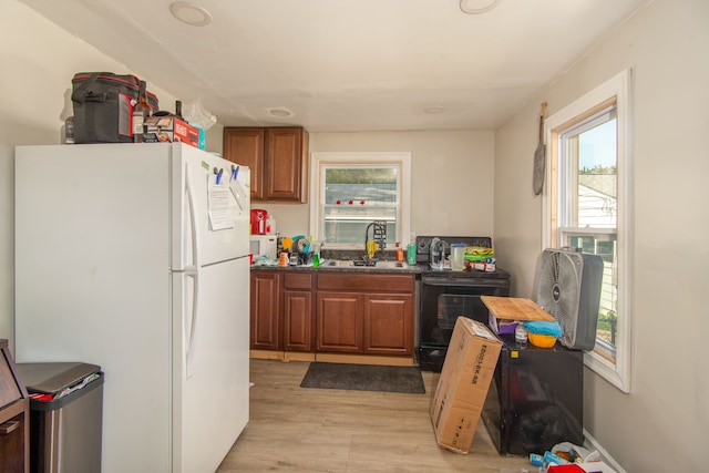 kitchen featuring black / electric stove, sink, white fridge, and light wood-type flooring