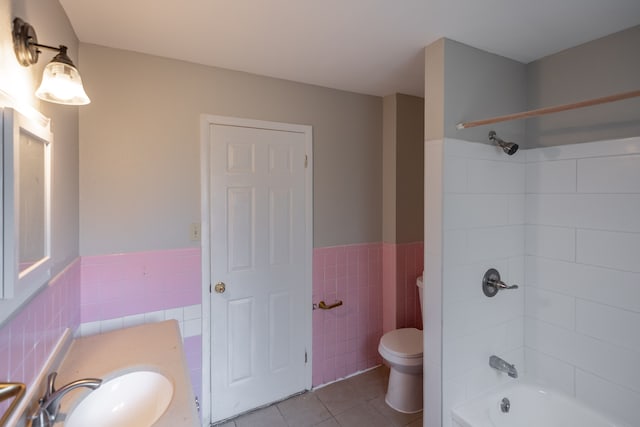 full bathroom featuring tile patterned flooring, bathing tub / shower combination, toilet, vanity, and tile walls