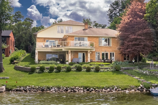 rear view of house with a lawn, a balcony, and a water view