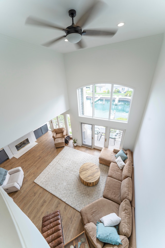 living room featuring a towering ceiling, hardwood / wood-style flooring, and ceiling fan