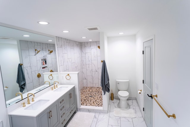 bathroom with vanity, toilet, and a tile shower