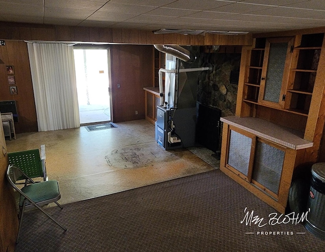 basement with wood walls, carpet floors, and heating unit