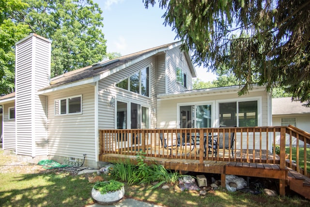 rear view of property with a deck, crawl space, and a chimney