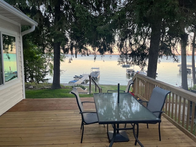 deck at dusk featuring outdoor dining area and a water view