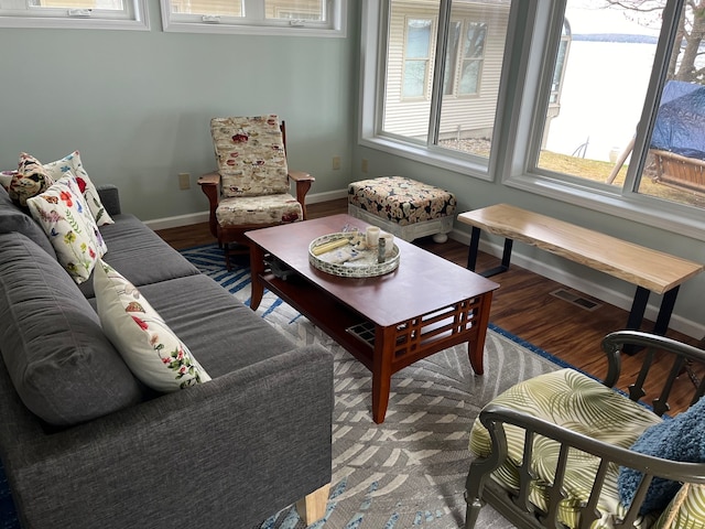 living area with wood finished floors, visible vents, and baseboards