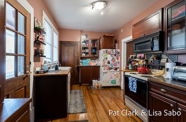 kitchen with decorative backsplash, white appliances, dark brown cabinetry, sink, and light hardwood / wood-style floors