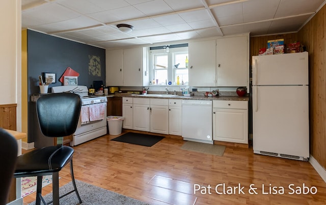 kitchen featuring wooden walls, light hardwood / wood-style flooring, white cabinets, and white appliances