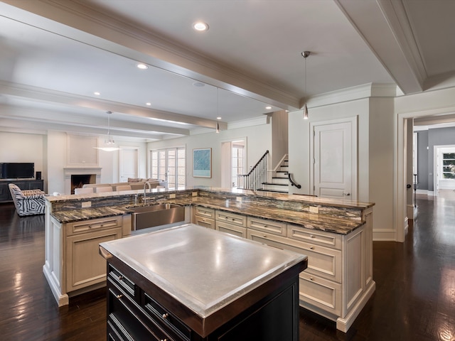 kitchen featuring pendant lighting, a kitchen island, sink, and dark wood-type flooring