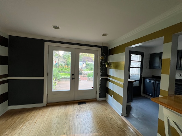 doorway with ornamental molding, light hardwood / wood-style floors, and french doors