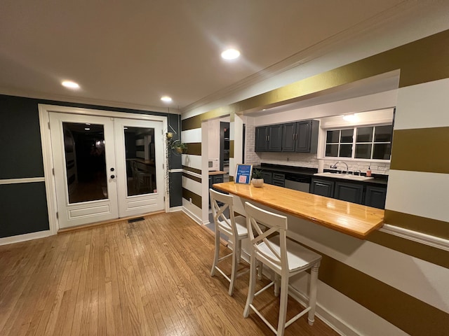 kitchen featuring dishwasher, sink, backsplash, ornamental molding, and light wood-type flooring