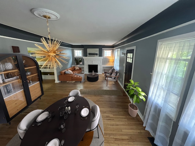 living room with hardwood / wood-style flooring, lofted ceiling, a brick fireplace, and a notable chandelier