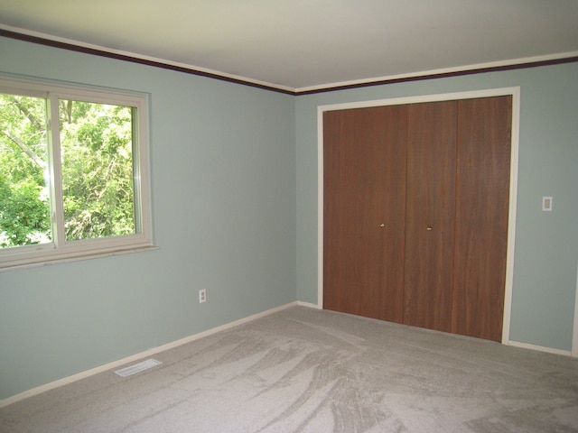 unfurnished bedroom with crown molding, a closet, and carpet floors