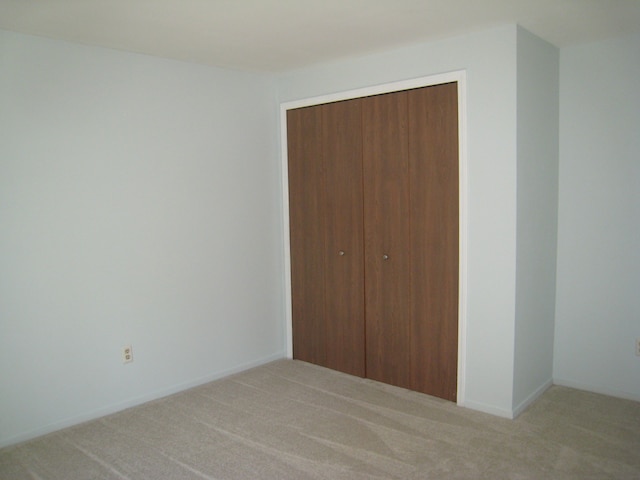 unfurnished bedroom featuring light colored carpet and a closet