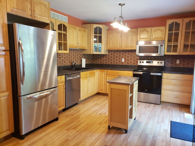 kitchen featuring a center island, sink, stainless steel appliances, light hardwood / wood-style flooring, and pendant lighting