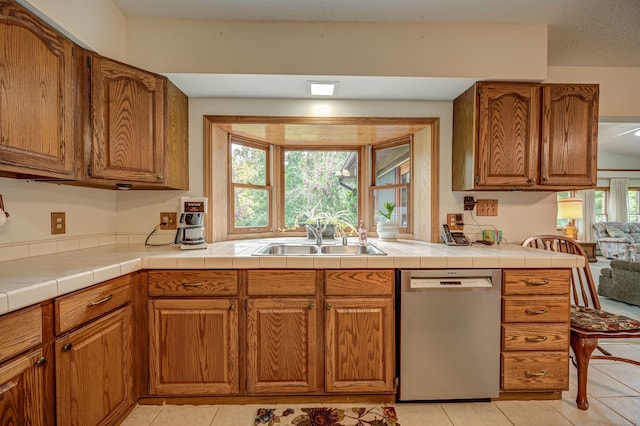 kitchen with tile countertops, dishwasher, plenty of natural light, and sink