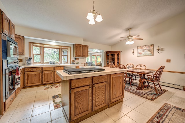 kitchen featuring tile counters, hanging light fixtures, stainless steel appliances, lofted ceiling, and a kitchen island