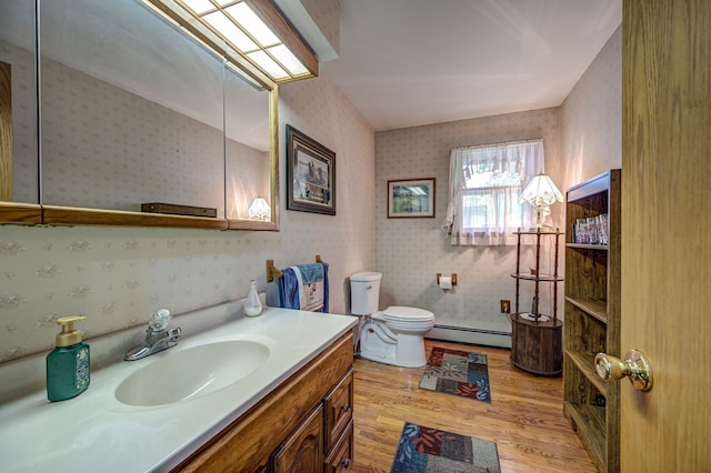 bathroom with vanity, hardwood / wood-style flooring, toilet, and baseboard heating