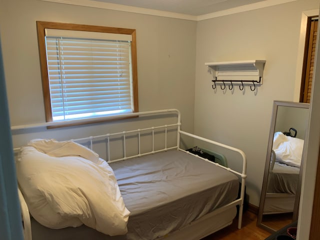 bedroom with hardwood / wood-style floors and ornamental molding