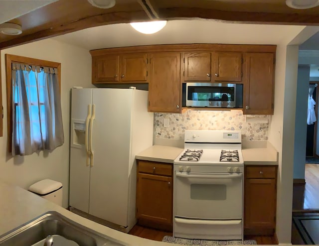 kitchen featuring white appliances, hardwood / wood-style flooring, and backsplash