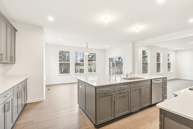 kitchen with sink, an island with sink, gray cabinets, and light hardwood / wood-style flooring