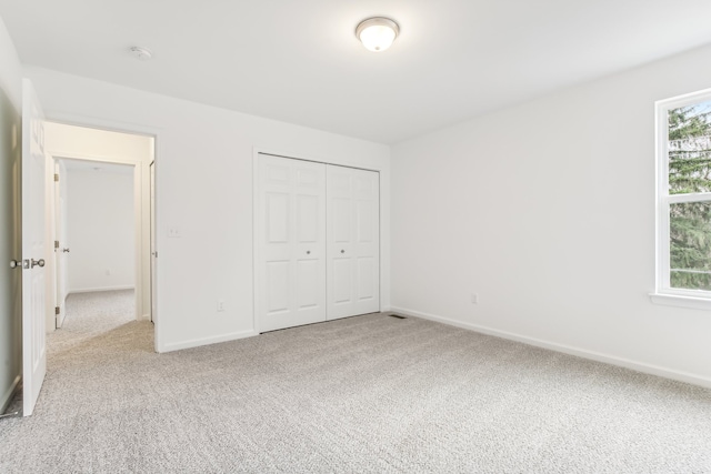 unfurnished bedroom featuring light colored carpet and a closet