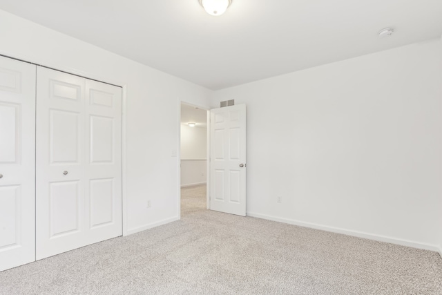 unfurnished bedroom featuring light carpet and a closet