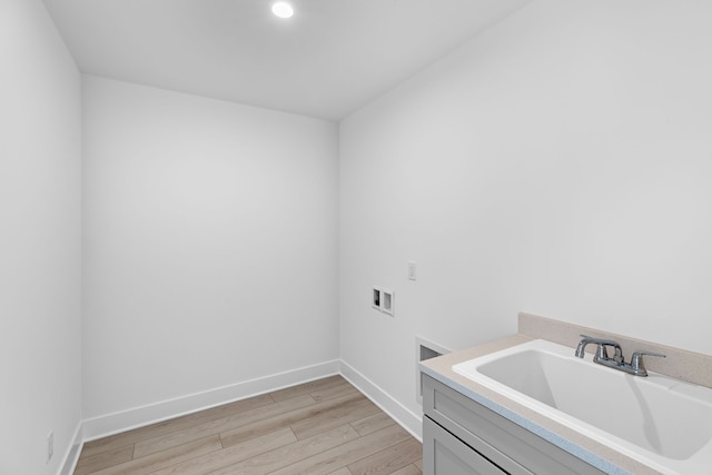 washroom featuring hookup for a washing machine, sink, cabinets, and light hardwood / wood-style flooring