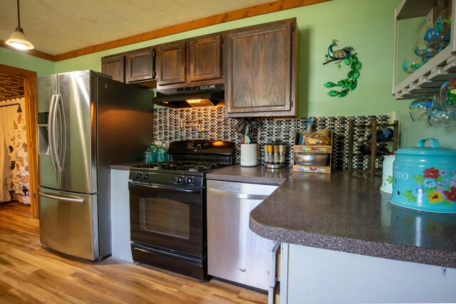 515 Locust St, Howard City, MI 49329 - kitchen featuring appliances with stainless steel finishes, under cabinet range hood, dark countertops, backsplash, and light wood finished floors