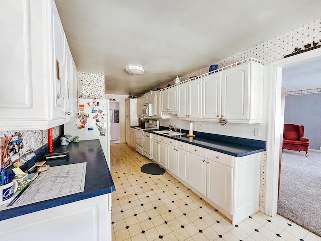 kitchen featuring electric stove, refrigerator, and white cabinets