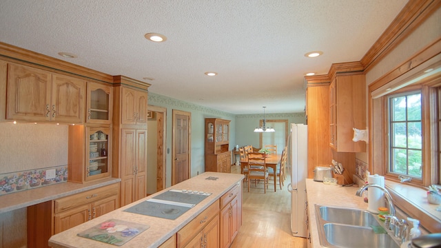 kitchen featuring sink, white fridge, pendant lighting, electric cooktop, and light wood-type flooring