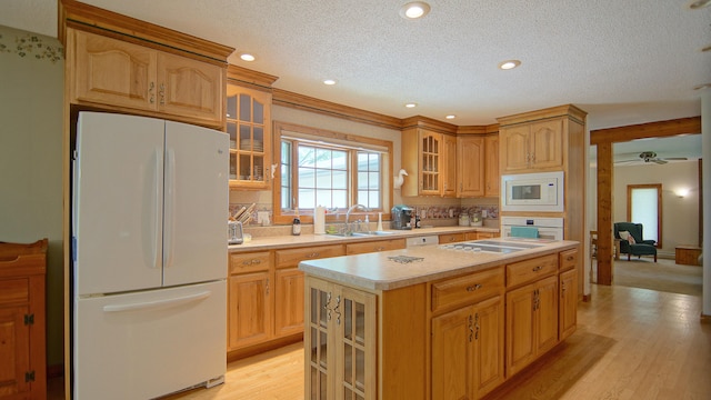 kitchen with sink, a kitchen island, white appliances, and light hardwood / wood-style flooring