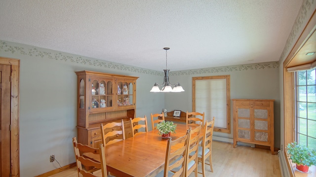 dining room with a textured ceiling, a baseboard radiator, light hardwood / wood-style flooring, and a notable chandelier