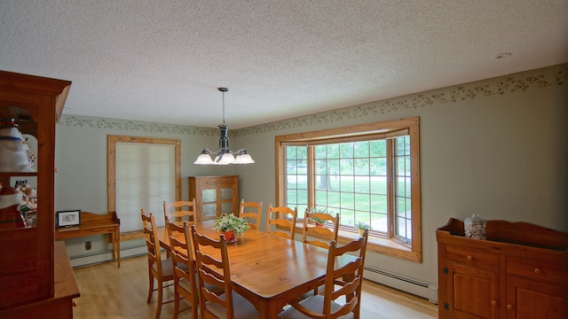 dining space with a textured ceiling, light hardwood / wood-style flooring, baseboard heating, and a notable chandelier