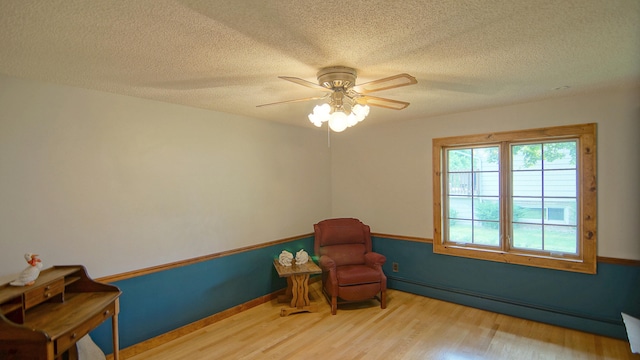 sitting room featuring a textured ceiling, ceiling fan, light hardwood / wood-style floors, and a baseboard radiator