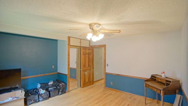 miscellaneous room with ceiling fan, wood-type flooring, and a textured ceiling