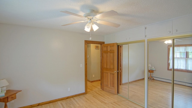 unfurnished bedroom featuring a textured ceiling, baseboard heating, light hardwood / wood-style flooring, and ceiling fan