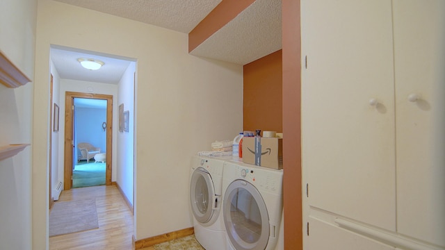 clothes washing area featuring washer and clothes dryer, light wood-type flooring, and a textured ceiling