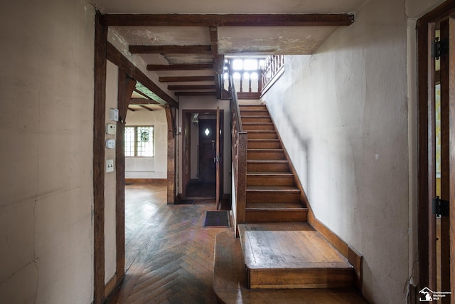 staircase with parquet flooring, beam ceiling, and plenty of natural light