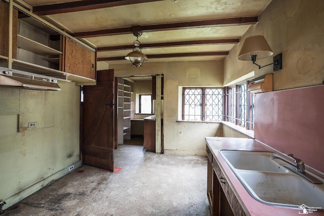 kitchen with beam ceiling, decorative light fixtures, and sink