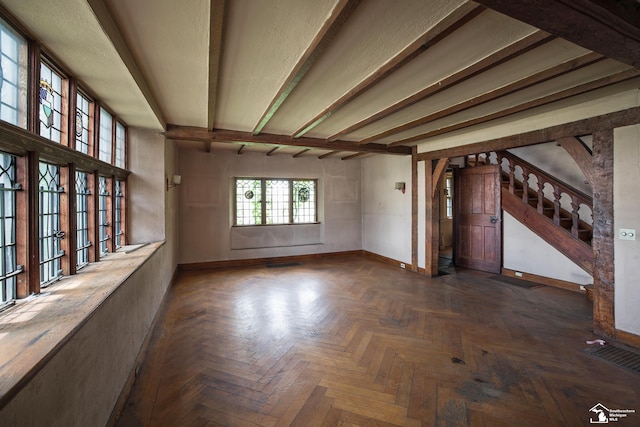 spare room with beamed ceiling and dark parquet flooring