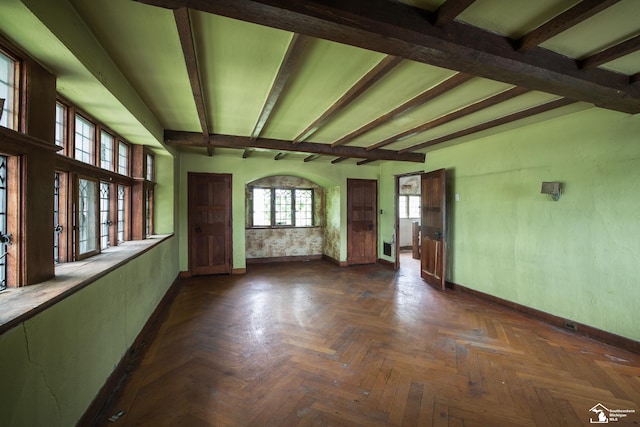 empty room with beam ceiling and dark parquet floors