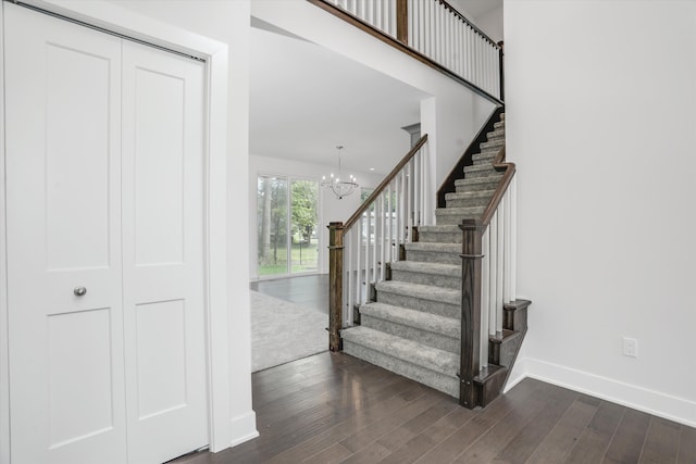 staircase with wood-type flooring and an inviting chandelier