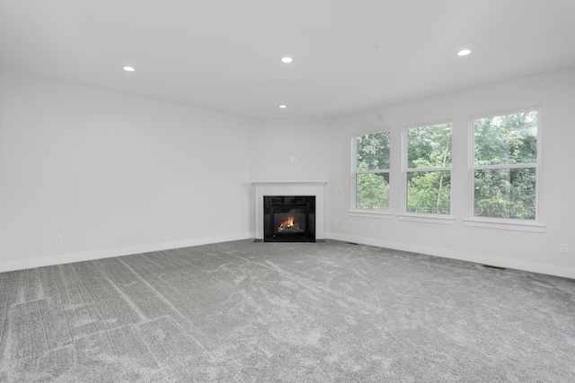 667 Allegheny Dr, South Lyon, MI 48178 - unfurnished living room featuring a fireplace with flush hearth, carpet flooring, recessed lighting, plenty of natural light, and baseboards