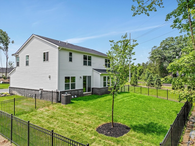 rear view of property featuring a yard and central air condition unit