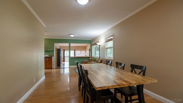 dining area with crown molding and light hardwood / wood-style flooring