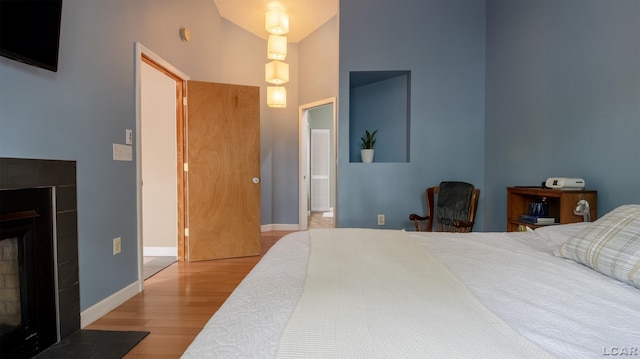 4241 Echo Cv, Manitou Beach, MI 49253 - bedroom featuring wood finished floors, a tile fireplace, baseboards, and a high ceiling