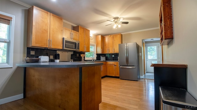 kitchen with sink, light hardwood / wood-style flooring, backsplash, crown molding, and appliances with stainless steel finishes